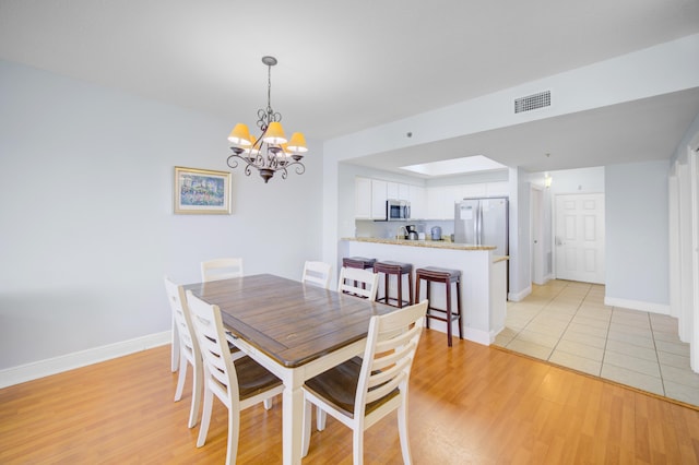 dining area with a chandelier and light hardwood / wood-style floors