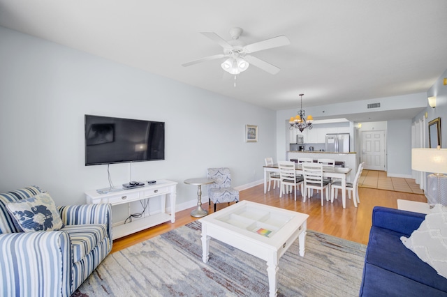 living room featuring ceiling fan with notable chandelier and wood-type flooring