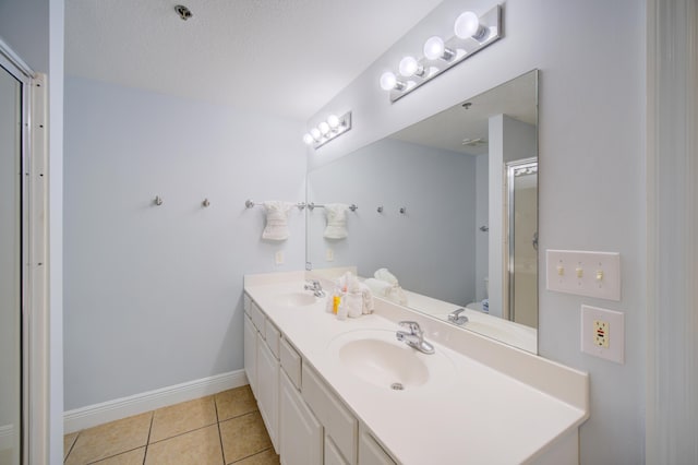 bathroom with tile patterned floors, vanity, a shower with door, and a textured ceiling