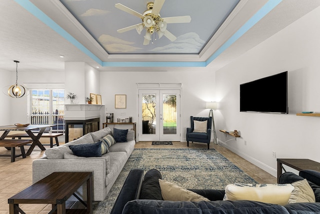 tiled living room featuring a raised ceiling, ceiling fan, french doors, and a multi sided fireplace