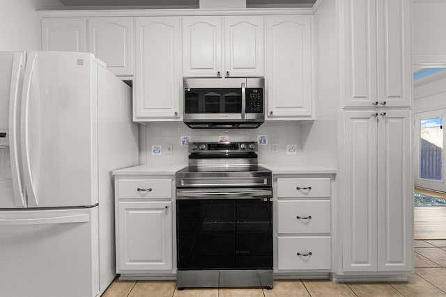 kitchen featuring white cabinets, decorative backsplash, light tile patterned flooring, and appliances with stainless steel finishes