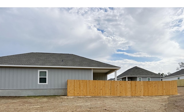 back of house featuring fence and roof with shingles