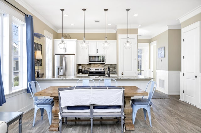 dining room with crown molding, light hardwood / wood-style flooring, and sink