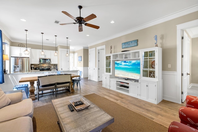 living room featuring ceiling fan, light wood-type flooring, and crown molding