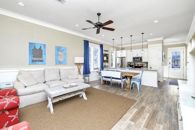 living room with ceiling fan, light wood-type flooring, and ornamental molding