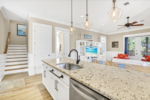 kitchen with light stone counters, ceiling fan, sink, white cabinets, and hanging light fixtures