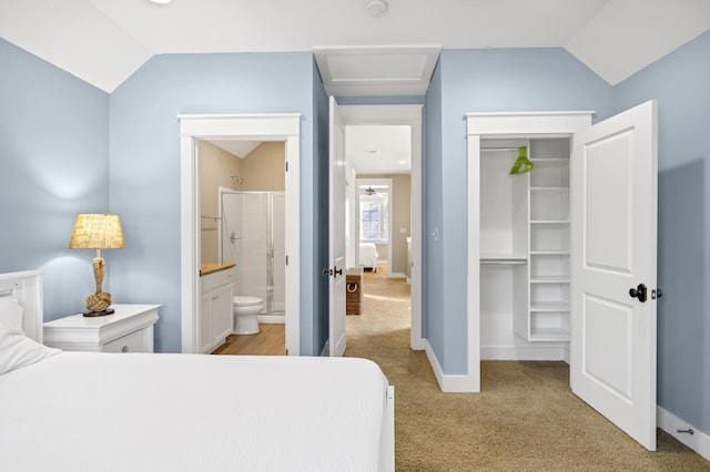 carpeted bedroom with ensuite bath, a closet, and vaulted ceiling