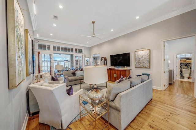 living room featuring ceiling fan, light wood-type flooring, and crown molding