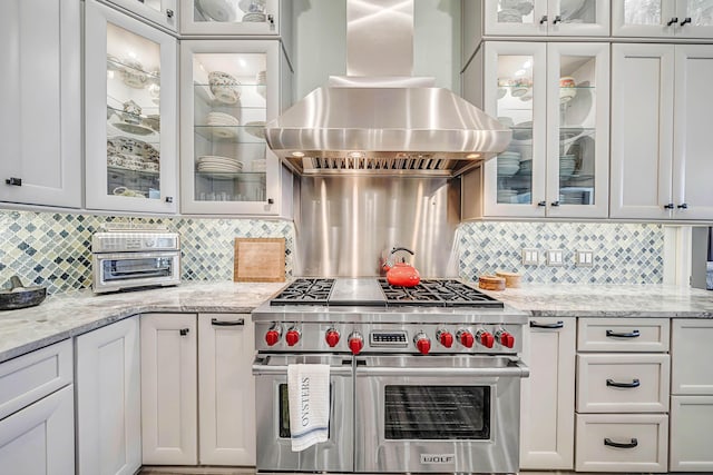 kitchen with white cabinetry, decorative backsplash, double oven range, and wall chimney range hood