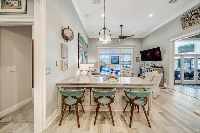 kitchen featuring kitchen peninsula, ornamental molding, a breakfast bar, light hardwood / wood-style flooring, and hanging light fixtures