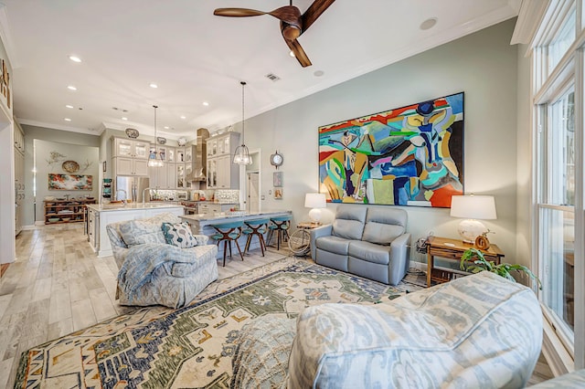 living room featuring ceiling fan, crown molding, and light hardwood / wood-style flooring