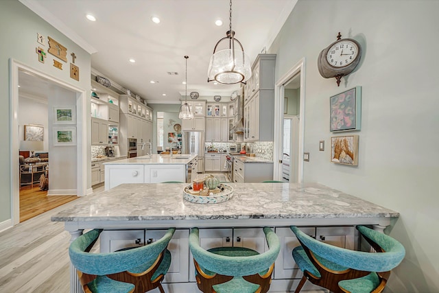 kitchen featuring gray cabinetry, backsplash, pendant lighting, light hardwood / wood-style floors, and a kitchen island