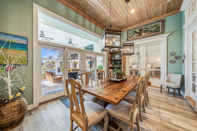 dining space with ceiling fan with notable chandelier, french doors, light wood-type flooring, and wood ceiling