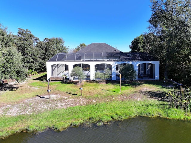 rear view of property featuring a yard, a water view, and a lanai