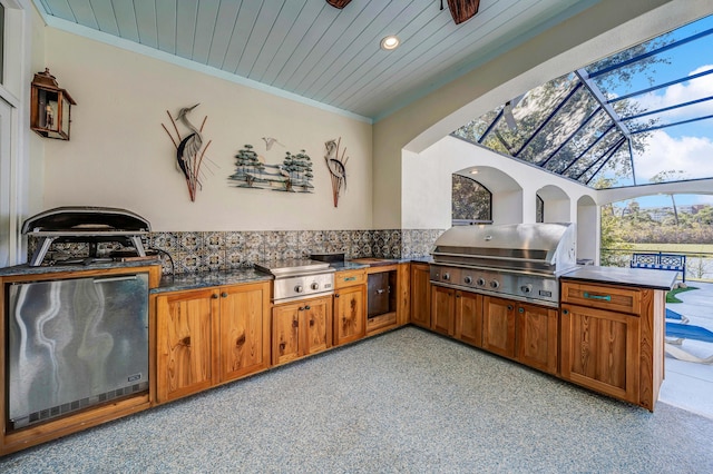 view of patio with a grill, glass enclosure, and exterior kitchen