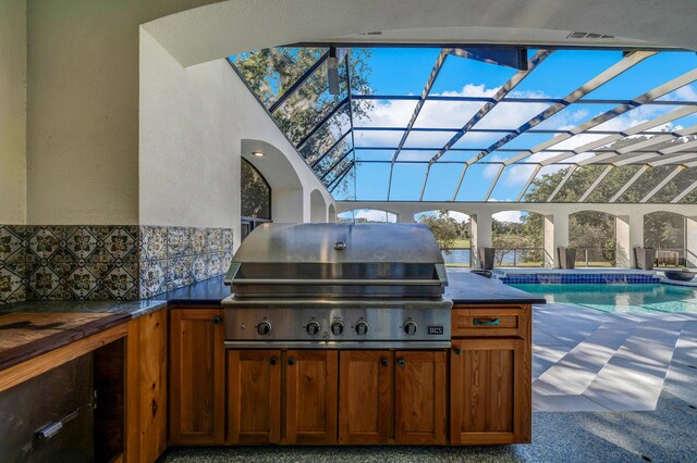 view of patio / terrace with grilling area, glass enclosure, and an outdoor kitchen