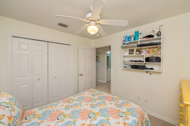 bedroom with ceiling fan, light colored carpet, a textured ceiling, and a closet