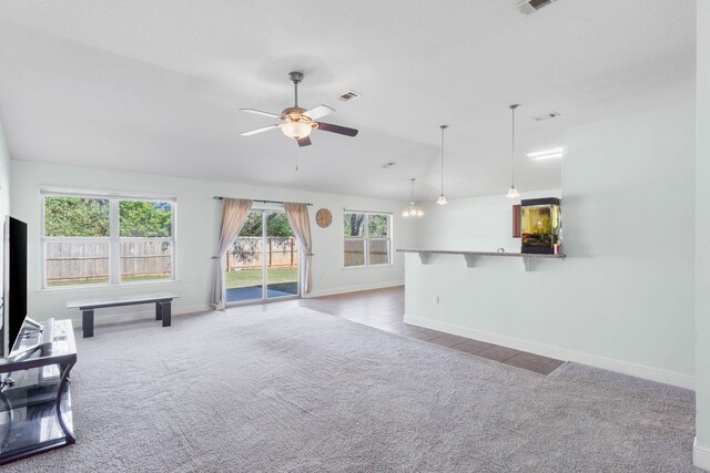 unfurnished living room with ceiling fan with notable chandelier and light carpet