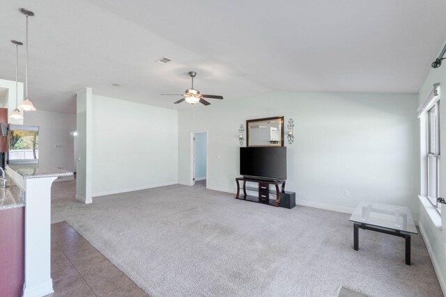 unfurnished living room featuring ceiling fan, a healthy amount of sunlight, light carpet, and vaulted ceiling