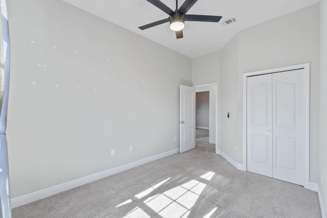 unfurnished bedroom featuring ceiling fan, a closet, and light carpet