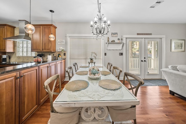 dining space with a notable chandelier, a healthy amount of sunlight, dark hardwood / wood-style flooring, and french doors