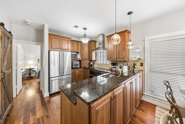 kitchen featuring sink, wall chimney exhaust hood, kitchen peninsula, decorative light fixtures, and black appliances