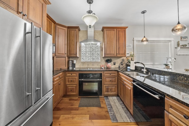 kitchen featuring pendant lighting, wall chimney exhaust hood, black appliances, and sink