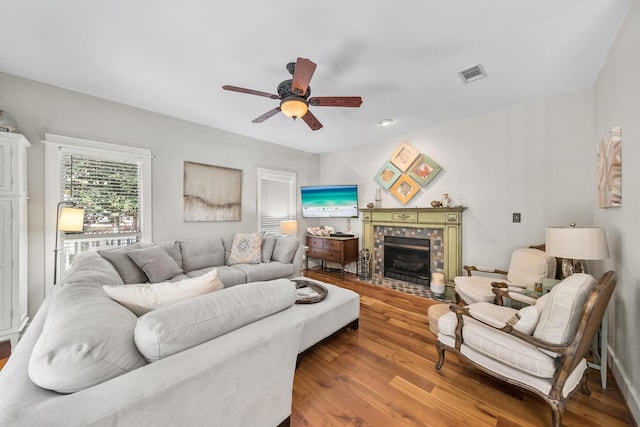 living room with ceiling fan, a fireplace, and wood-type flooring