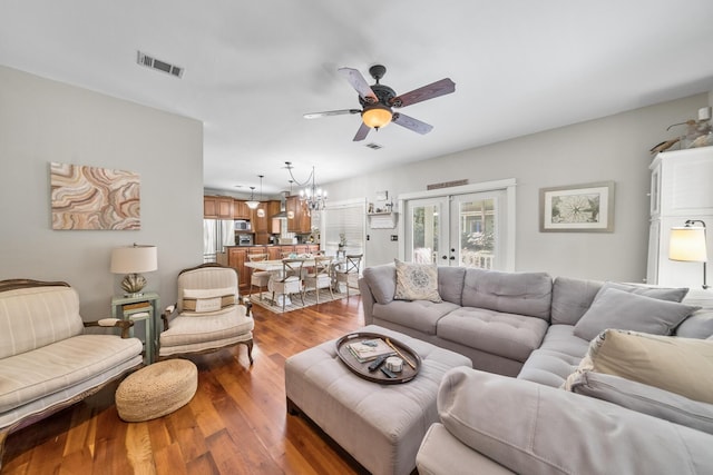 living room featuring ceiling fan with notable chandelier, wood-type flooring, and french doors