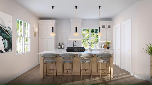 kitchen with white cabinets, a center island with sink, hanging light fixtures, and sink