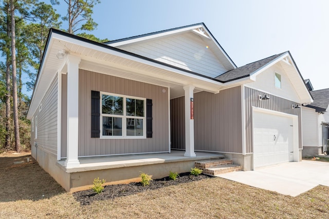 view of front of property featuring a garage, covered porch, driveway, and a shingled roof