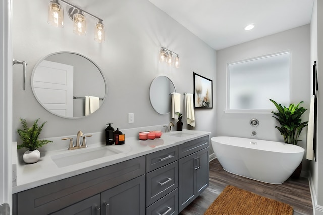 bathroom featuring wood-type flooring, vanity, and a tub to relax in