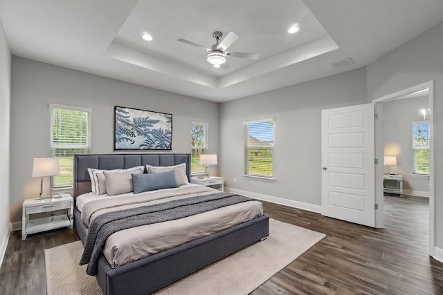 bedroom featuring dark wood-type flooring, ceiling fan, and a tray ceiling