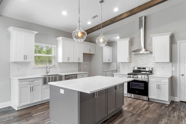 kitchen with a kitchen island, appliances with stainless steel finishes, white cabinets, hanging light fixtures, and wall chimney range hood