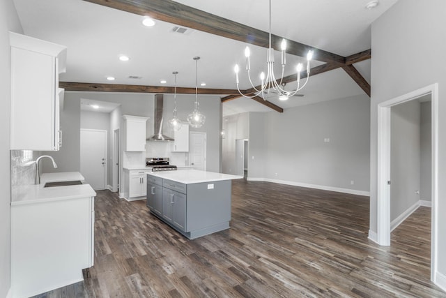 kitchen featuring sink, white cabinetry, a kitchen island, decorative light fixtures, and wall chimney exhaust hood