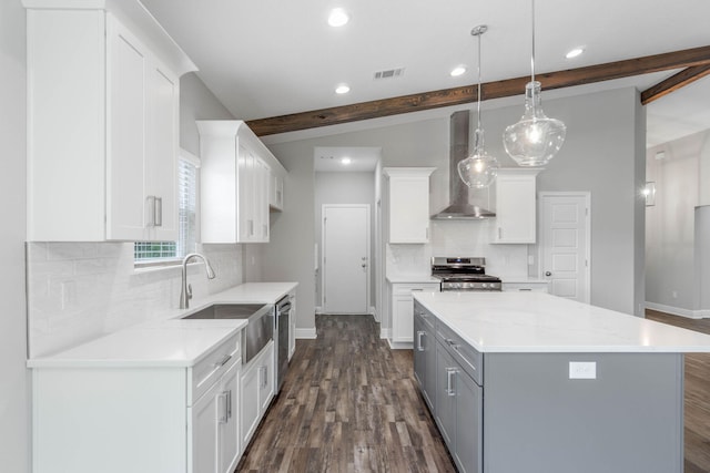 kitchen featuring wall chimney exhaust hood, white cabinetry, hanging light fixtures, beamed ceiling, and stainless steel appliances