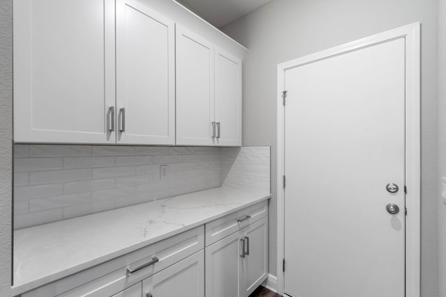 bar featuring tasteful backsplash, light stone countertops, and white cabinets