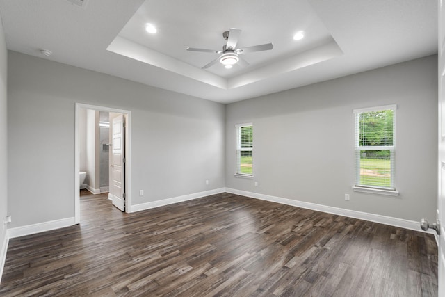 unfurnished room with a tray ceiling, dark hardwood / wood-style floors, and ceiling fan