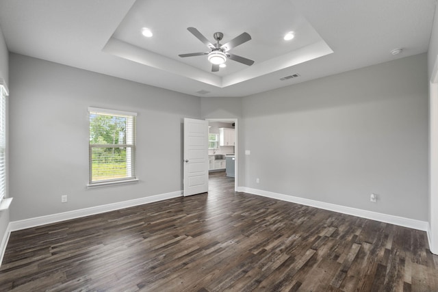 unfurnished room with dark wood-type flooring, ceiling fan, and a tray ceiling