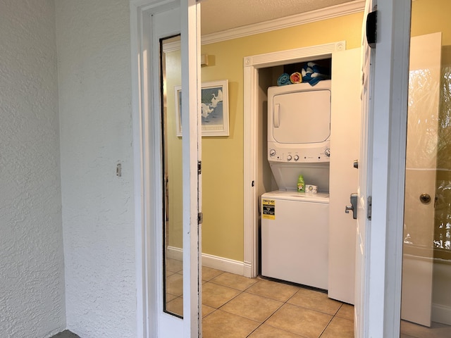 clothes washing area with stacked washer and dryer, light tile patterned floors, and ornamental molding