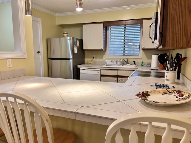 kitchen with stainless steel refrigerator, dishwasher, tile counters, crown molding, and pendant lighting