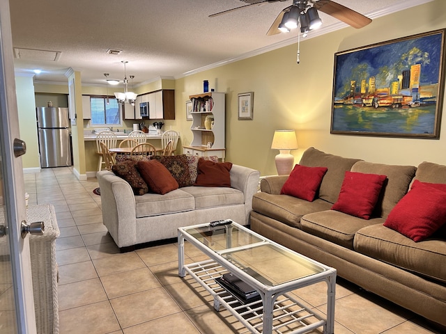 living room with a textured ceiling, ceiling fan, light tile patterned floors, and crown molding