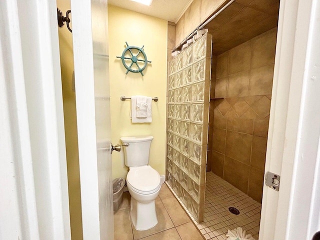 bathroom featuring tile patterned floors, toilet, and a tile shower