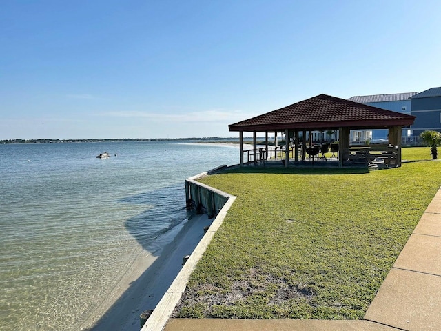 dock area with a gazebo, a water view, and a lawn