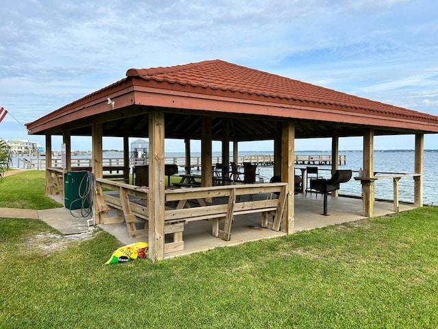 view of dock with a water view and a lawn