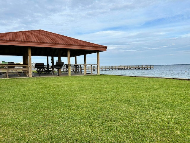 view of dock featuring a lawn and a water view