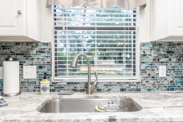 kitchen with white cabinets, light stone counters, and sink