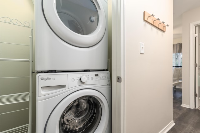 laundry room with stacked washer and dryer and dark wood-type flooring