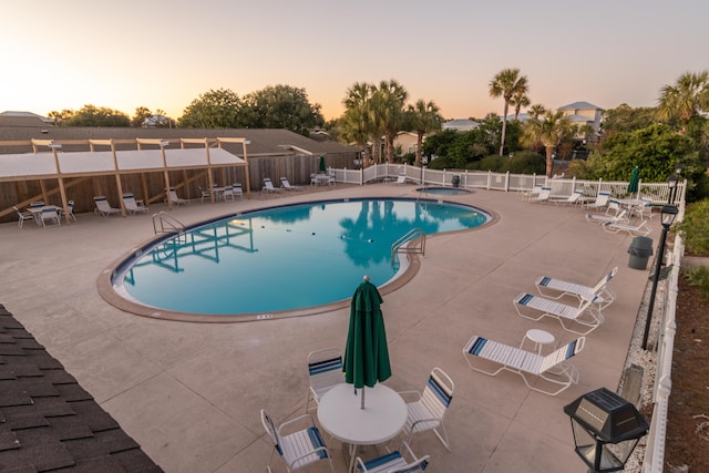 pool at dusk with a patio area