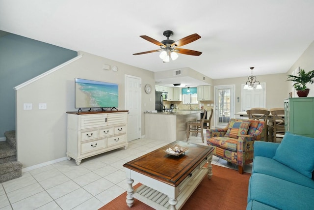 tiled living room featuring ceiling fan with notable chandelier and sink